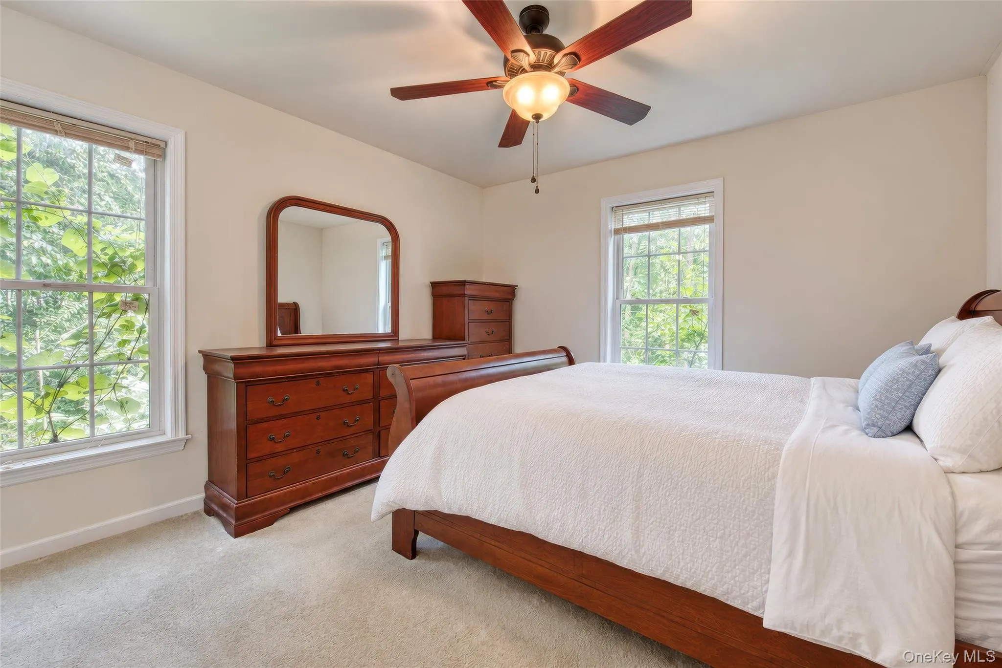 Neutral-toned walls, two large windows, a ceiling fan with integrated lighting, and carpeted flooring Neutral-toned walls, two large windows, a ceiling fan with integrated lighting, and carpeted flooring