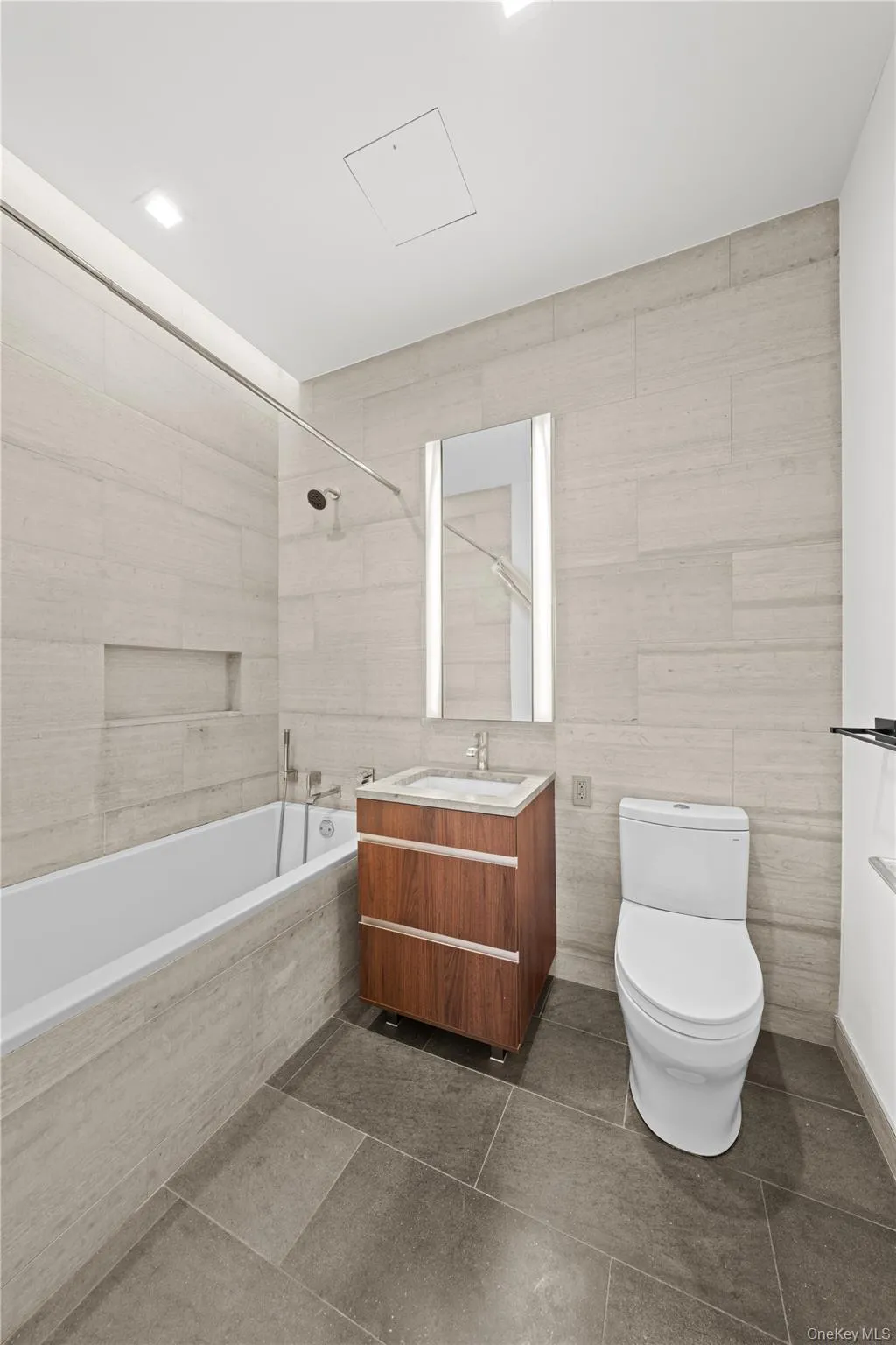Bathroom featuring vanity, tile walls, tiled shower / bath combo, and dark tile patterned floors Bathroom featuring vanity, tile walls, tiled shower / bath combo, and dark tile patterned floors