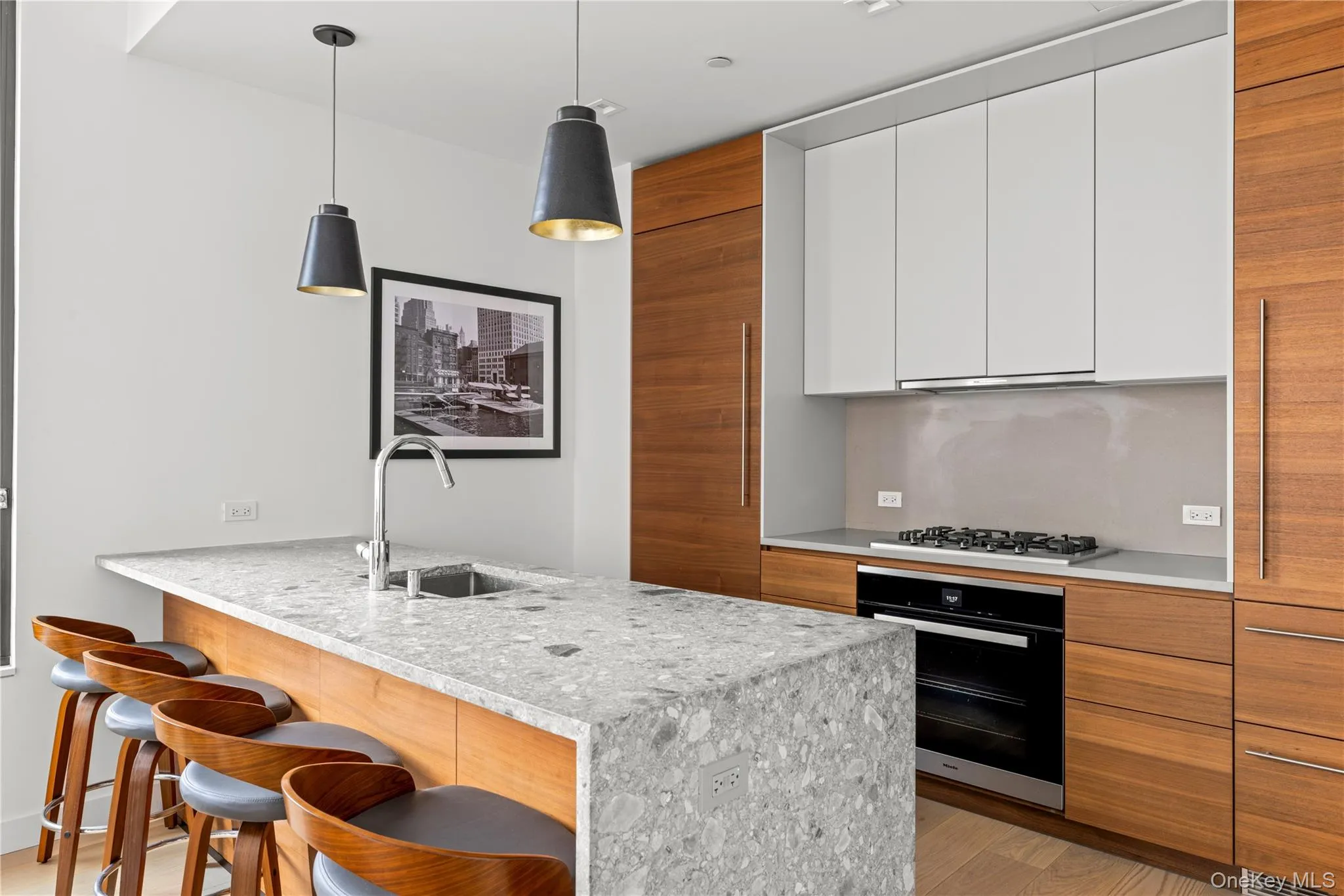 Kitchen featuring brown cabinets, modern cabinets, a peninsula, black oven, and a breakfast bar area Kitchen featuring brown cabinets, modern cabinets, a peninsula, black oven, and a breakfast bar area