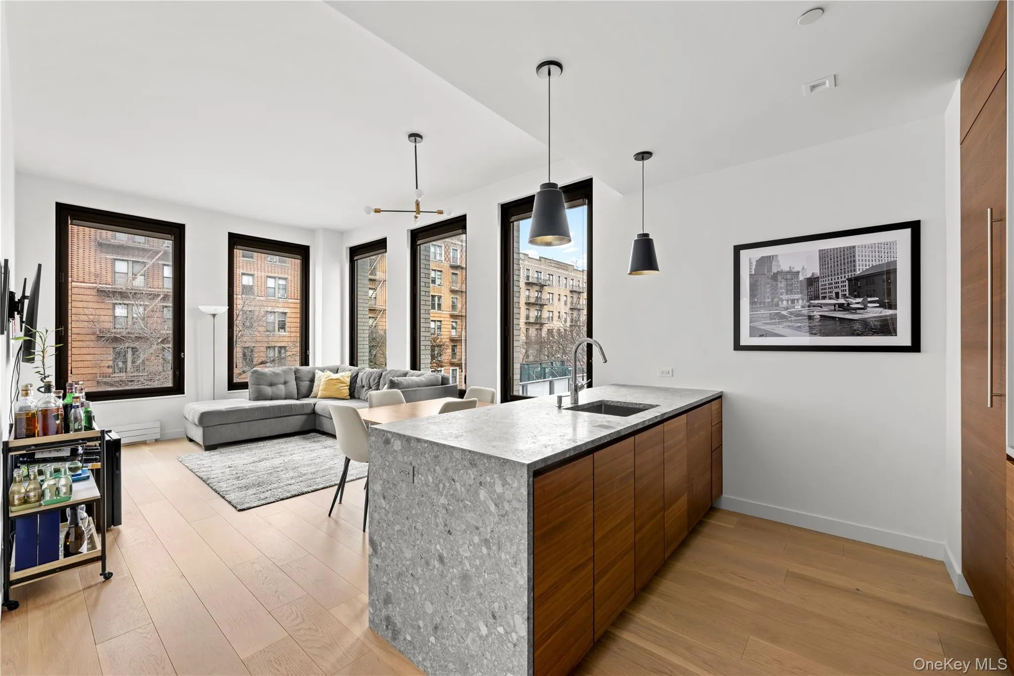 Kitchen featuring decorative light fixtures, modern cabinets, light wood-style floors, a peninsula, and brown cabinetry Kitchen featuring decorative light fixtures, modern cabinets, light wood-style floors, a peninsula, and brown cabinetry