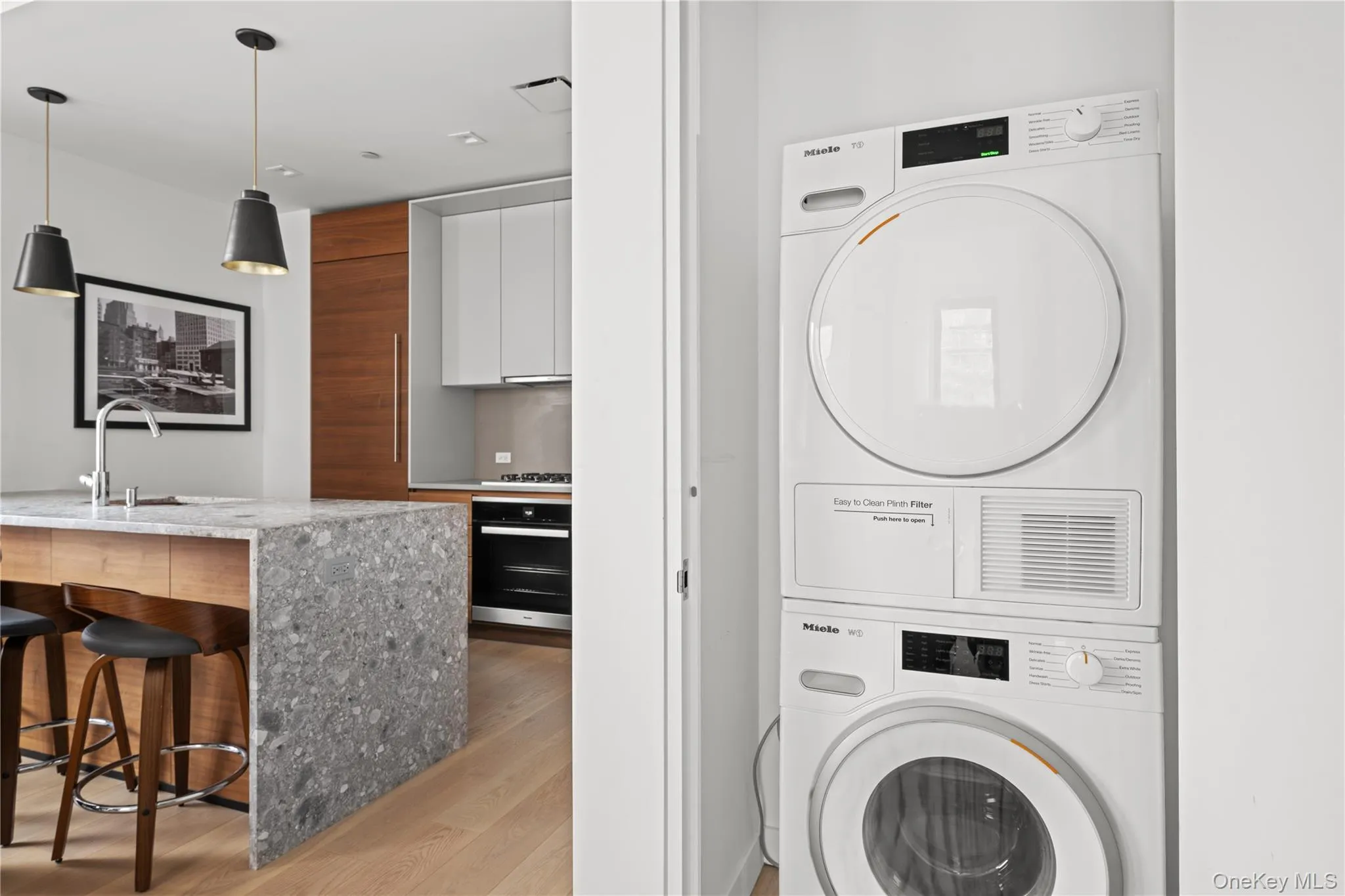 Washroom featuring stacked washer and clothes dryer and light wood finished floors Washroom featuring stacked washer and clothes dryer and light wood finished floors