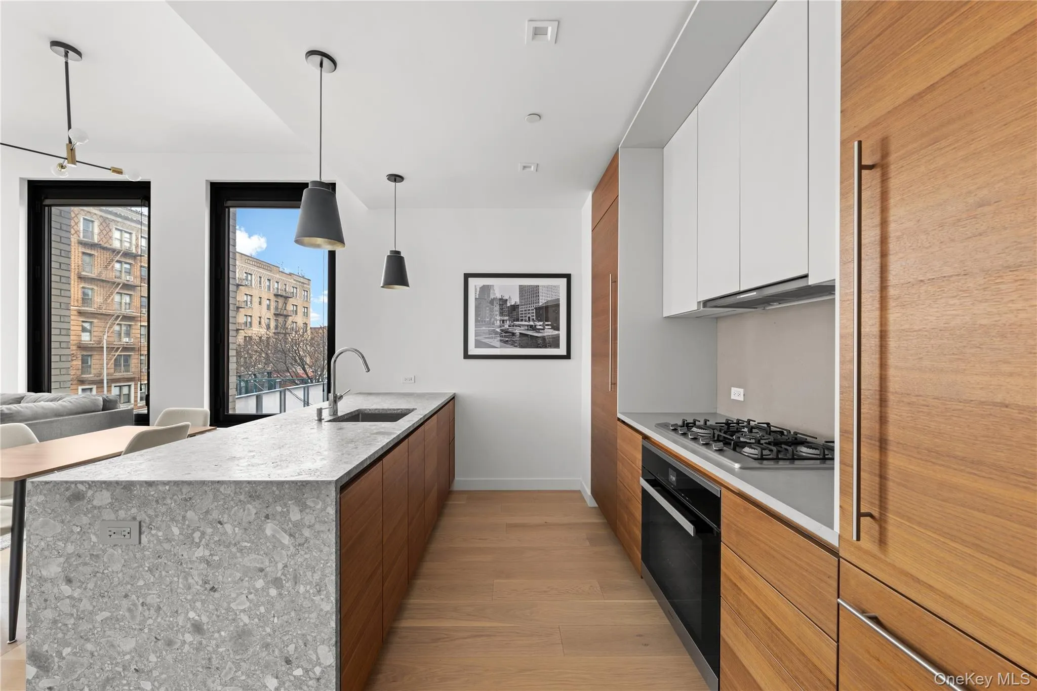 Kitchen with a peninsula, light wood finished floors, white cabinetry, hanging light fixtures, and black oven Kitchen with a peninsula, light wood finished floors, white cabinetry, hanging light fixtures, and black oven