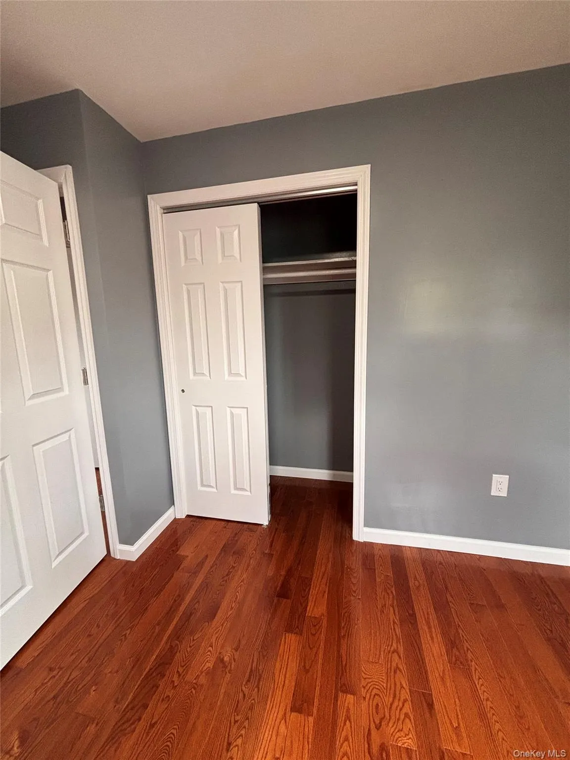 Hardwood flooring, painted walls, white trim, and a bi-fold closet door Hardwood flooring, painted walls, white trim, and a bi-fold closet door