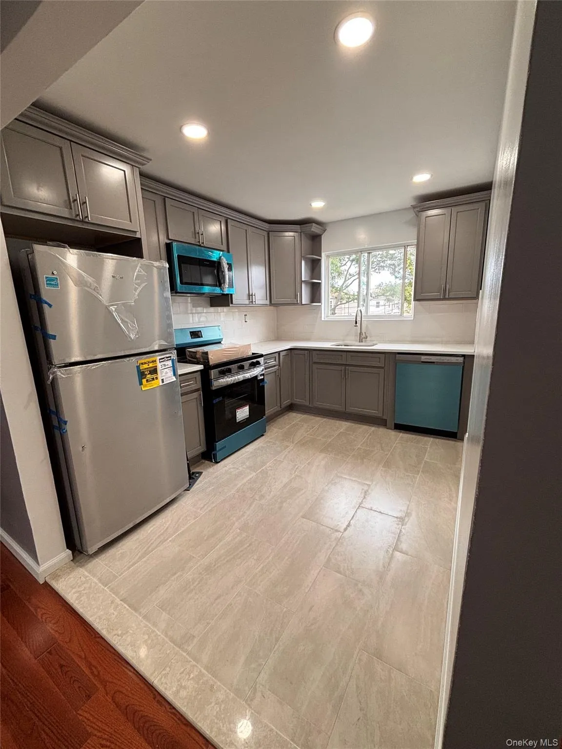 Recessed lighting illuminating a kitchen featuring gray shaker-style cabinetry, a tile backsplash Recessed lighting illuminating a kitchen featuring gray shaker-style cabinetry, a tile backsplash