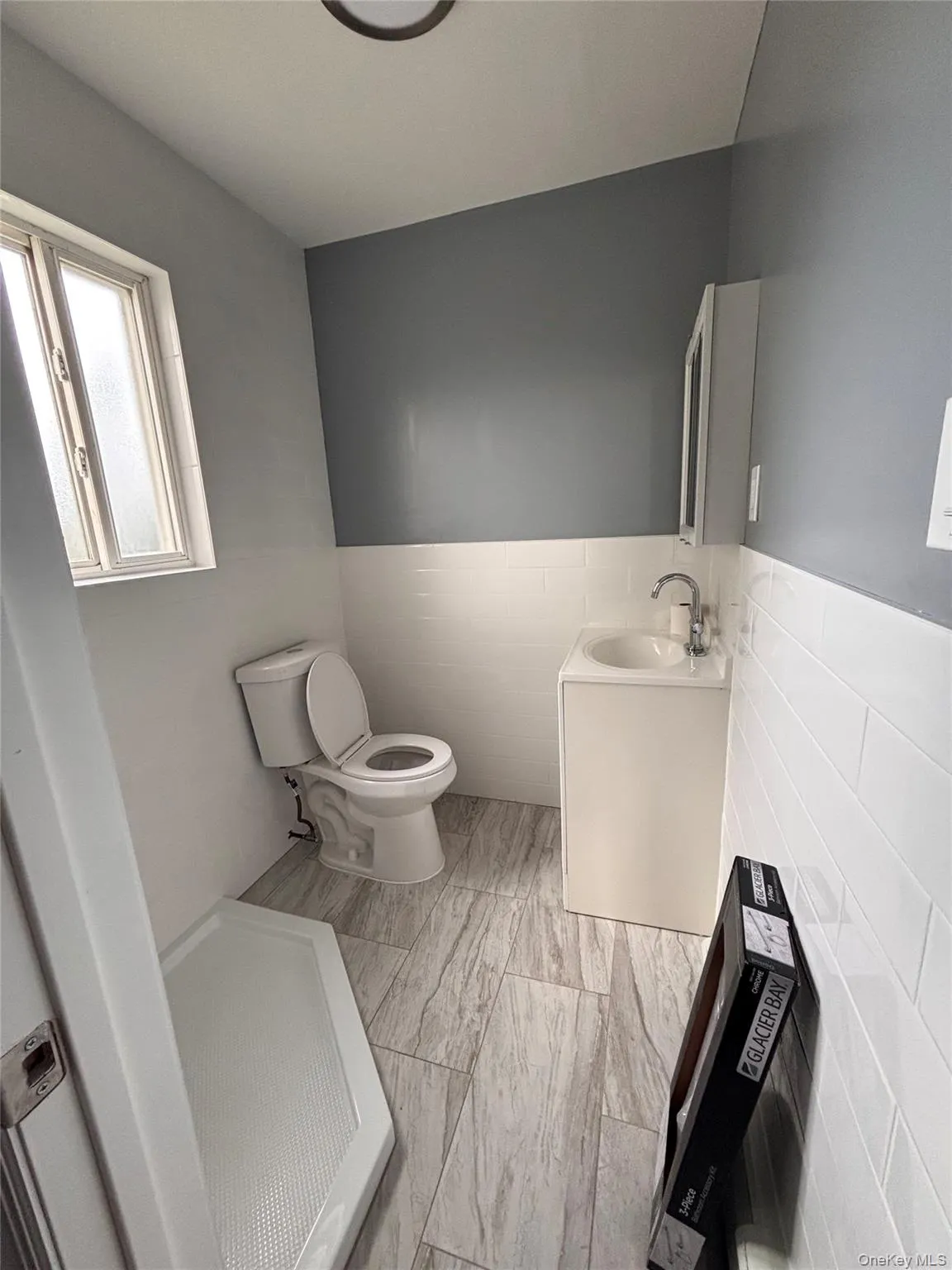 Tile flooring, white wall tiling, window with frosted glass, recessed ceiling lighting, and vanity with integrated sink Tile flooring, white wall tiling, window with frosted glass, recessed ceiling lighting, and vanity with integrated sink