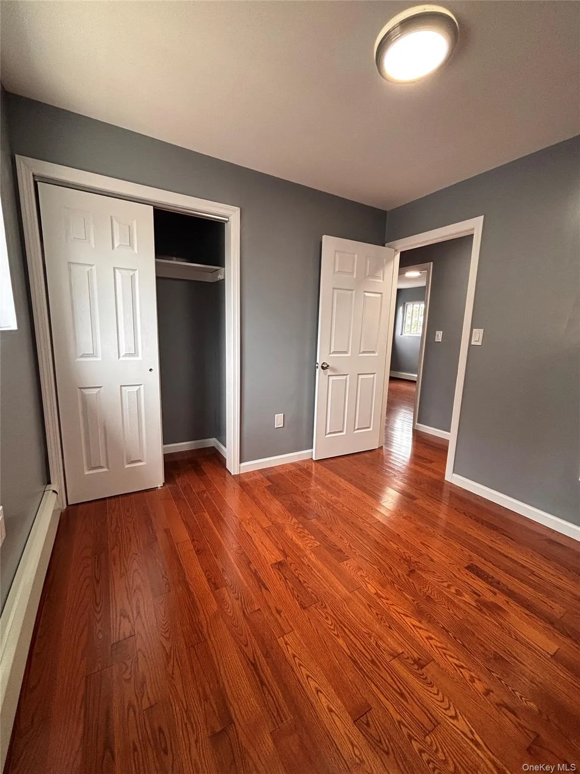 Hardwood flooring throughout, gray wall paint, white trim, and a flush-mount ceiling light fixture Hardwood flooring throughout, gray wall paint, white trim, and a flush-mount ceiling light fixture