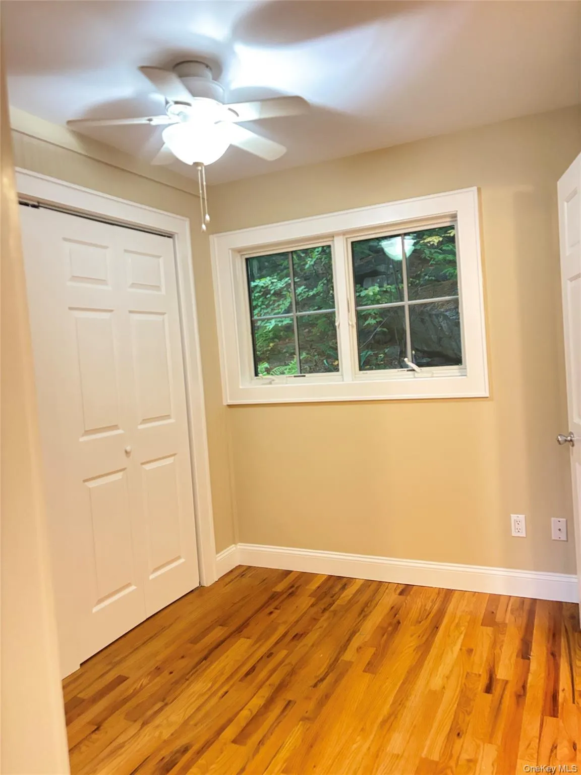 Hardwood flooring, white trim, bi-fold closet doors, and a ceiling fan with integrated lighting Hardwood flooring, white trim, bi-fold closet doors, and a ceiling fan with integrated lighting
