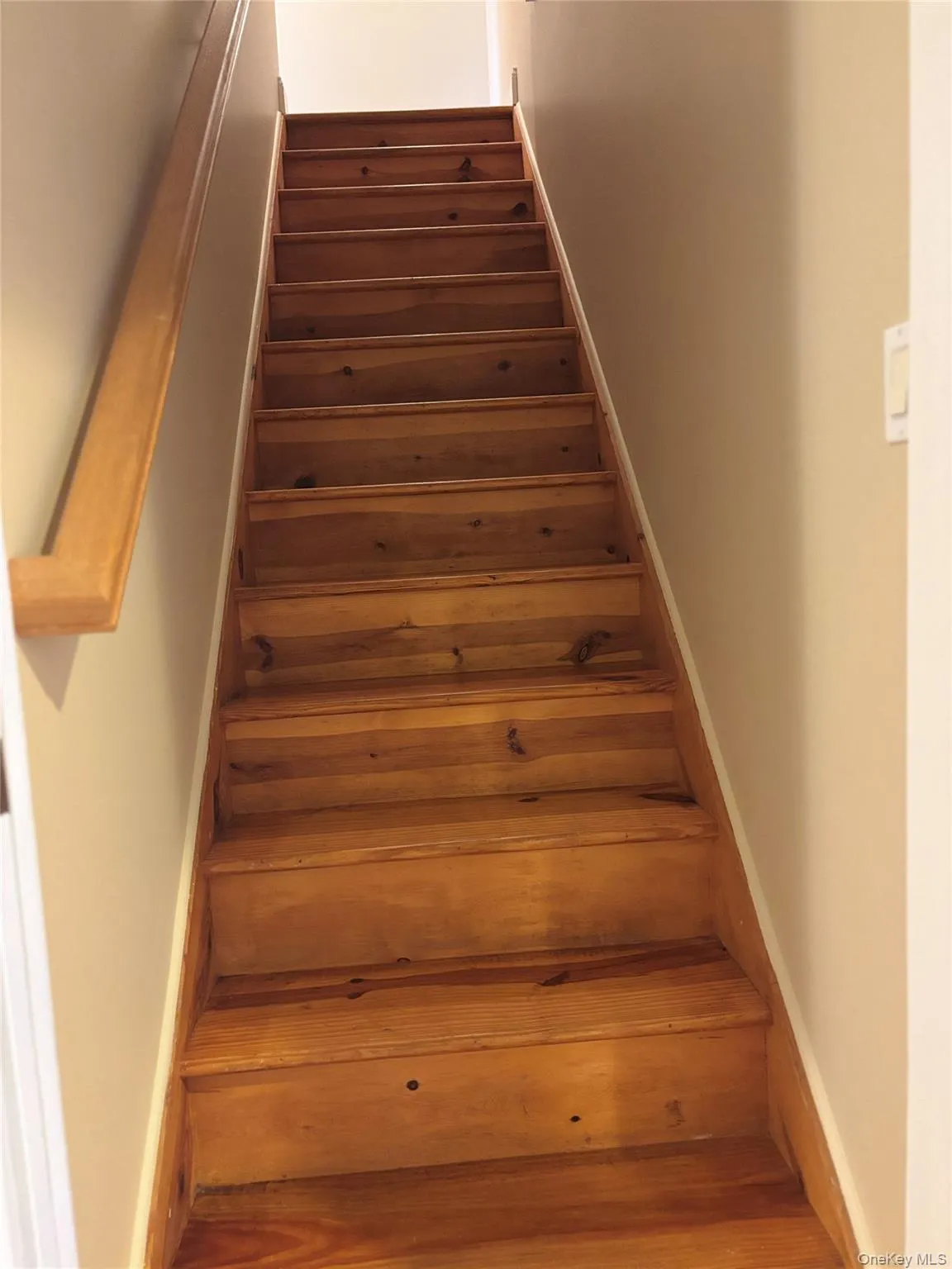 Staircase featuring wood steps and a wood handrail leads to third floor bedroom and bath Staircase featuring wood steps and a wood handrail leads to third floor bedroom and bath