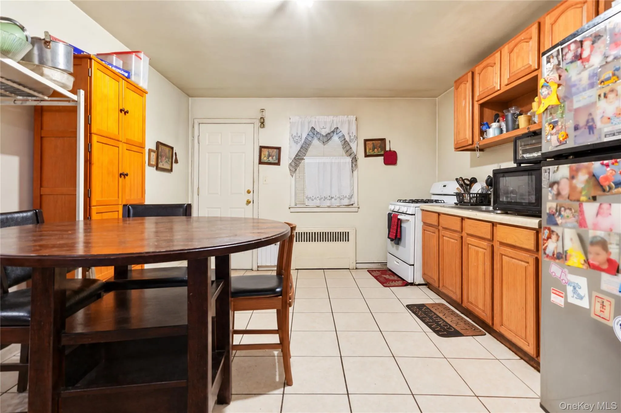 Kitchen featuring wood-finish cabinetry, tile flooring, and a white paneled door Kitchen featuring wood-finish cabinetry, tile flooring, and a white paneled door