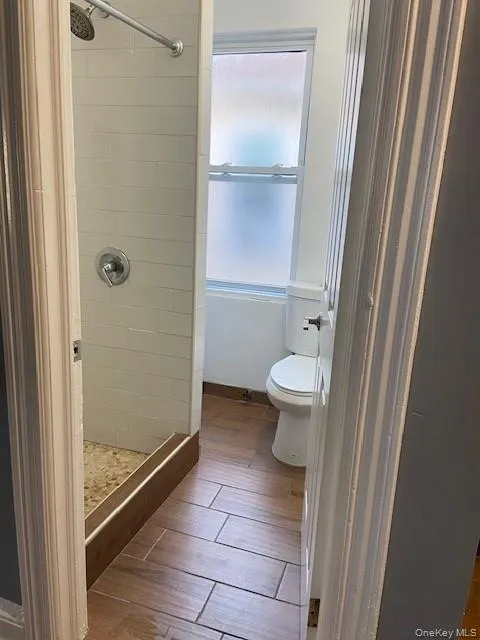 Renovated full bathroom with newly subway tiled shower, rain shower head, wood-finish tile flooring, and frosted window. Renovated full bathroom with newly subway tiled shower, rain shower head, wood-finish tile flooring, and frosted window.