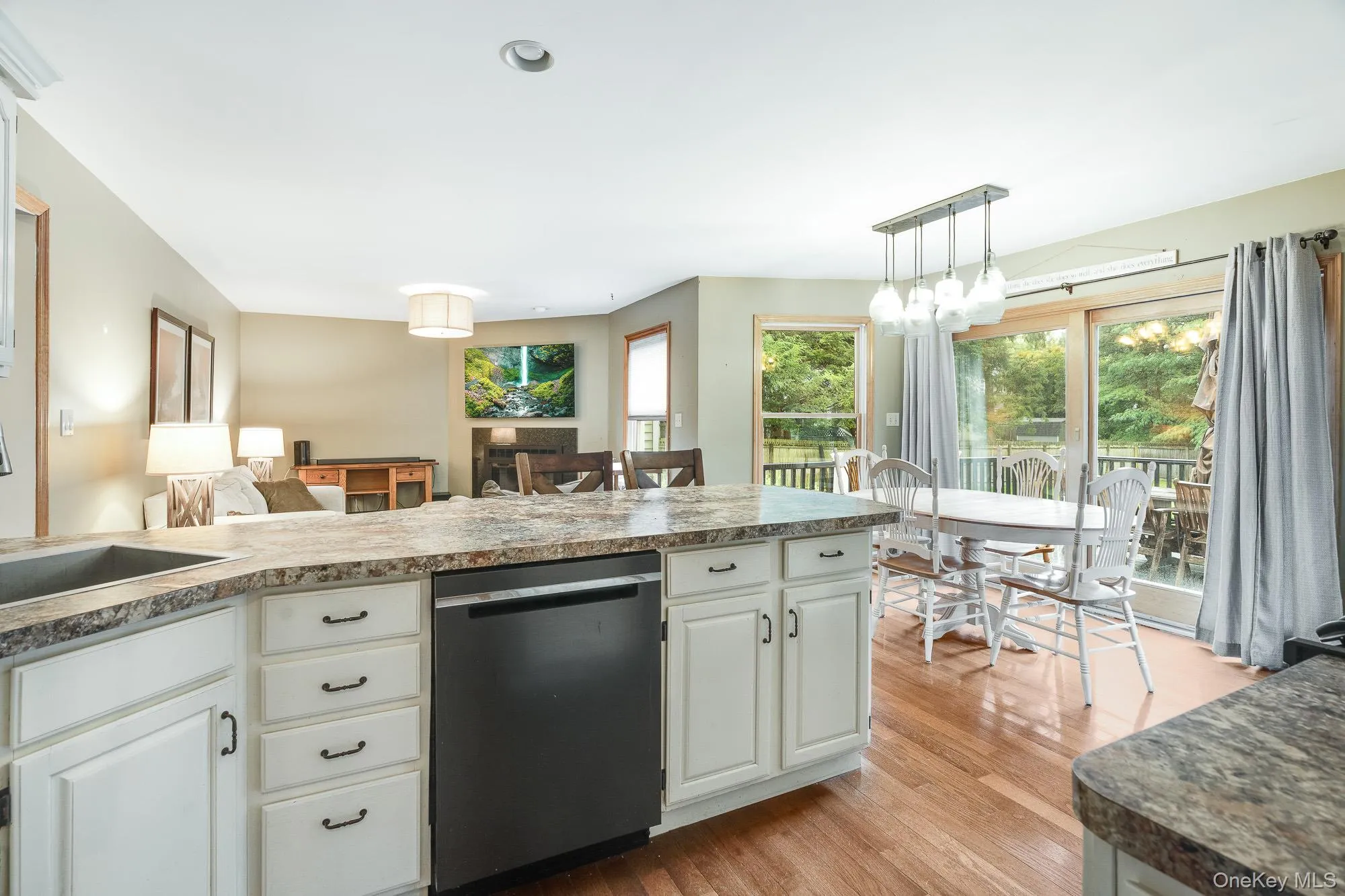 Kitchen featuring dishwashing machine, light wood finished floors, white cabinetry, pendant lighting, and recessed lighting Kitchen featuring dishwashing machine, light wood finished floors, white cabinetry, pendant lighting, and recessed lighting
