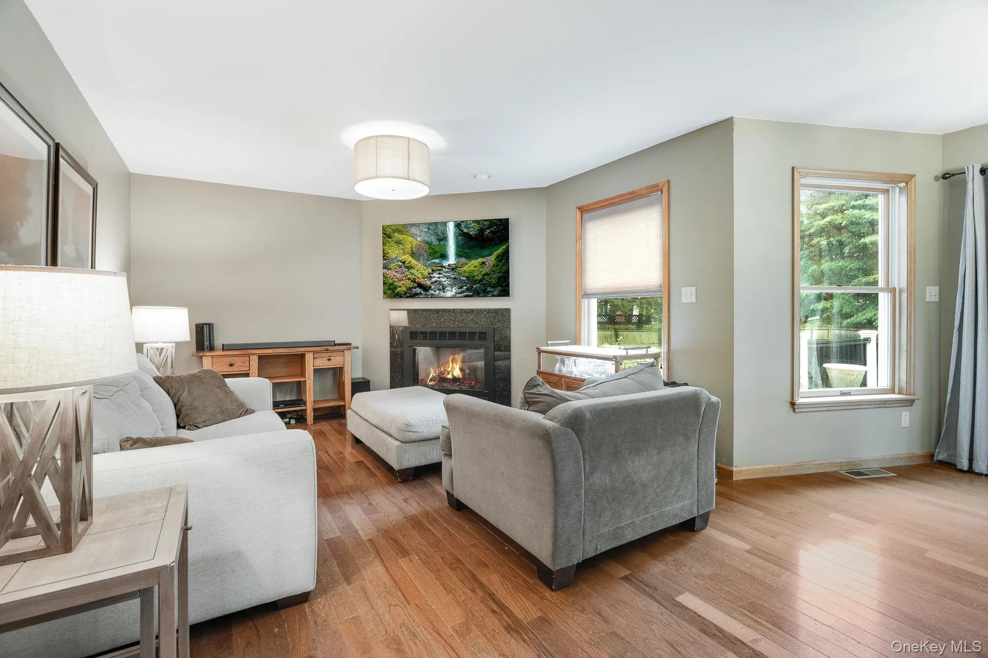 Living room with a tiled fireplace and wood-type flooring Living room with a tiled fireplace and wood-type flooring