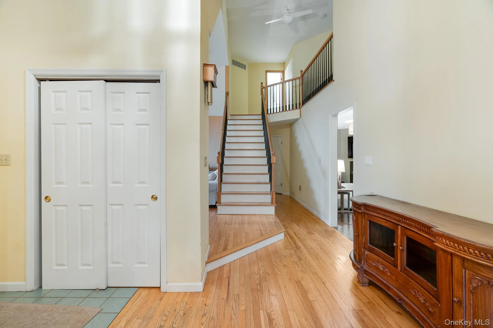 Staircase with wood finished floors, a towering ceiling, and a ceiling fan Staircase with wood finished floors, a towering ceiling, and a ceiling fan