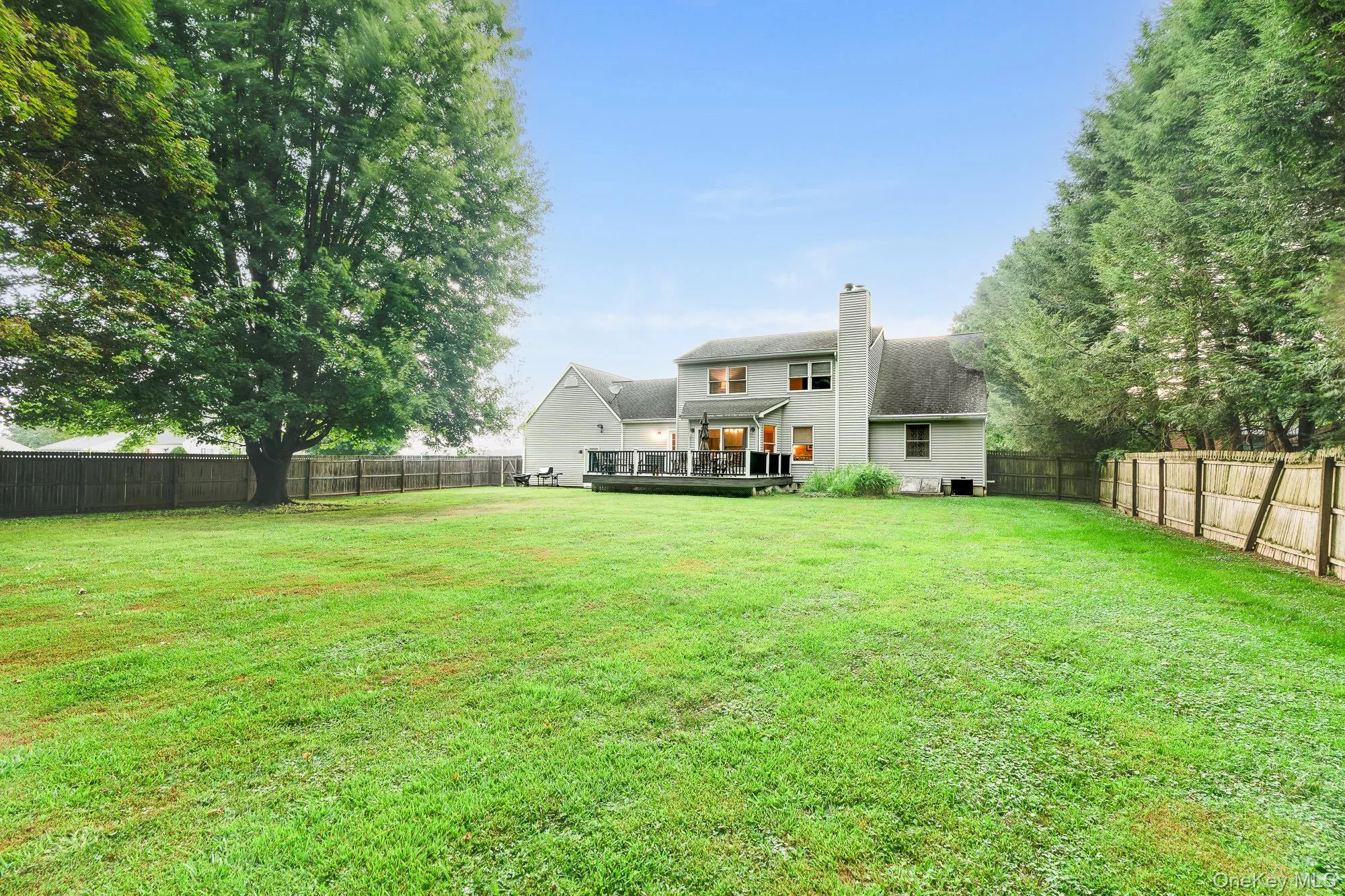 Back of house with a deck, a fenced backyard, and a chimney Back of house with a deck, a fenced backyard, and a chimney