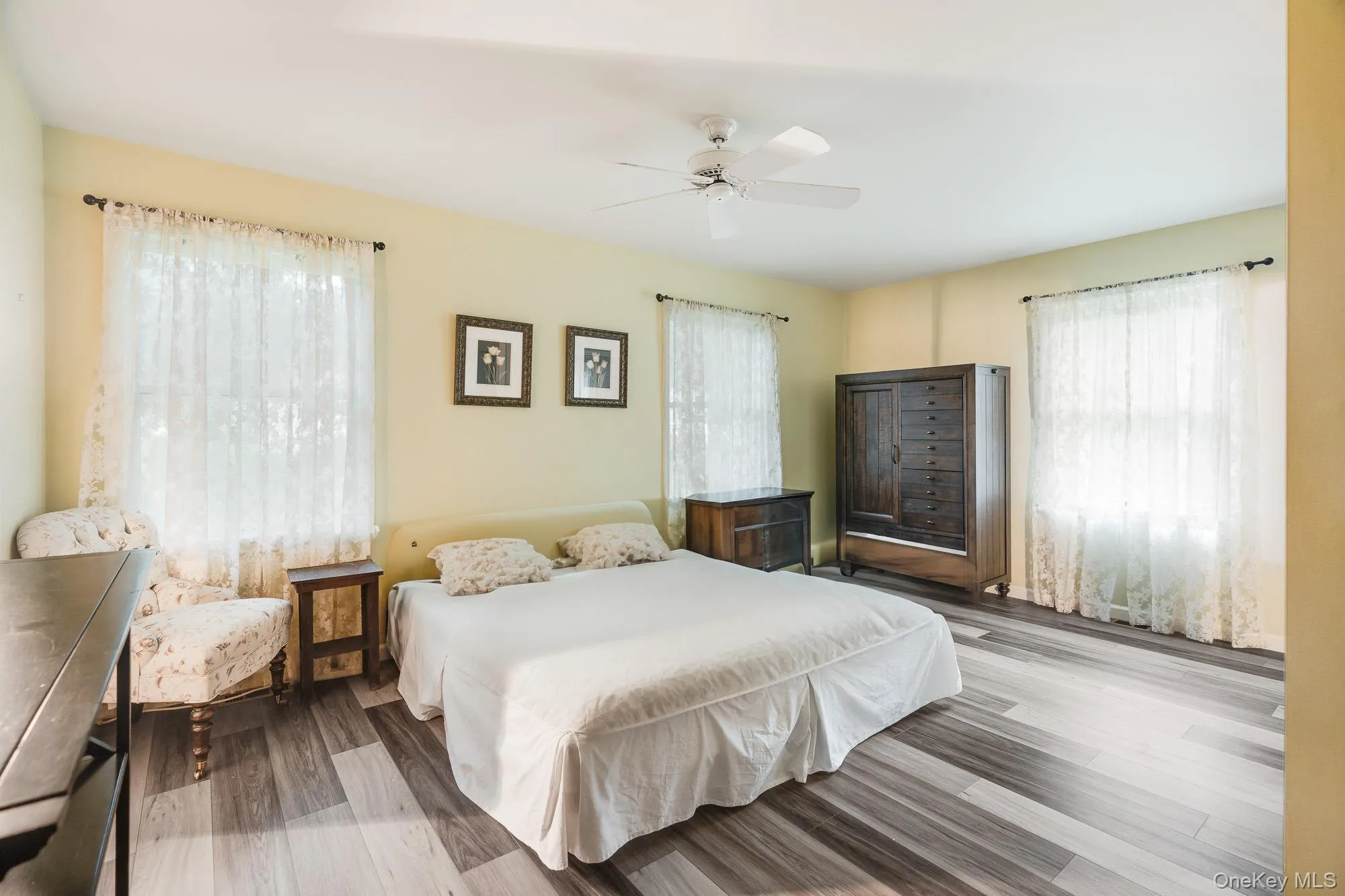 Bedroom featuring multiple windows, wood finished floors, and a ceiling fan Bedroom featuring multiple windows, wood finished floors, and a ceiling fan