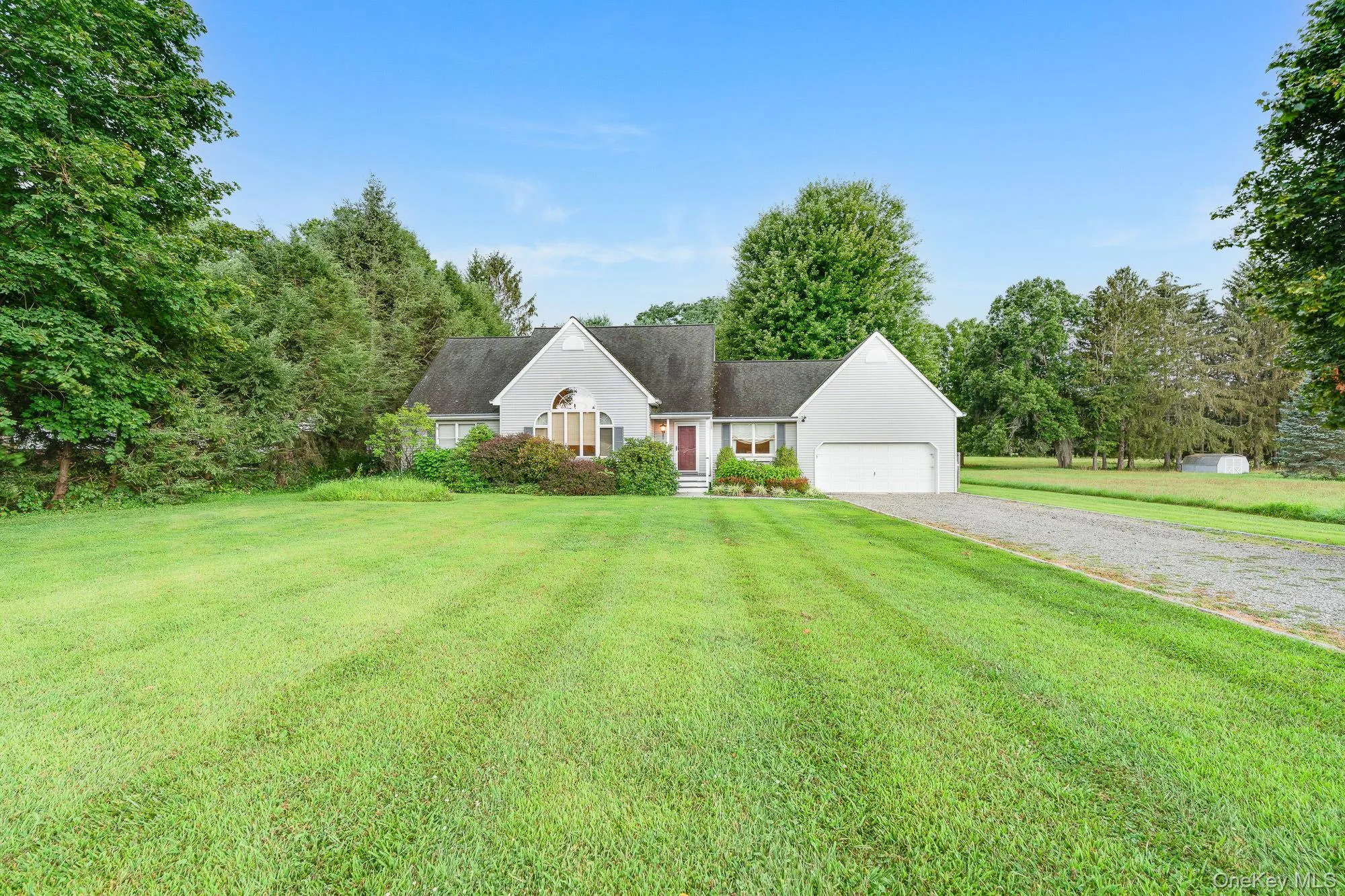 Cape cod house with gravel driveway, a garage, and a front yard Cape cod house with gravel driveway, a garage, and a front yard