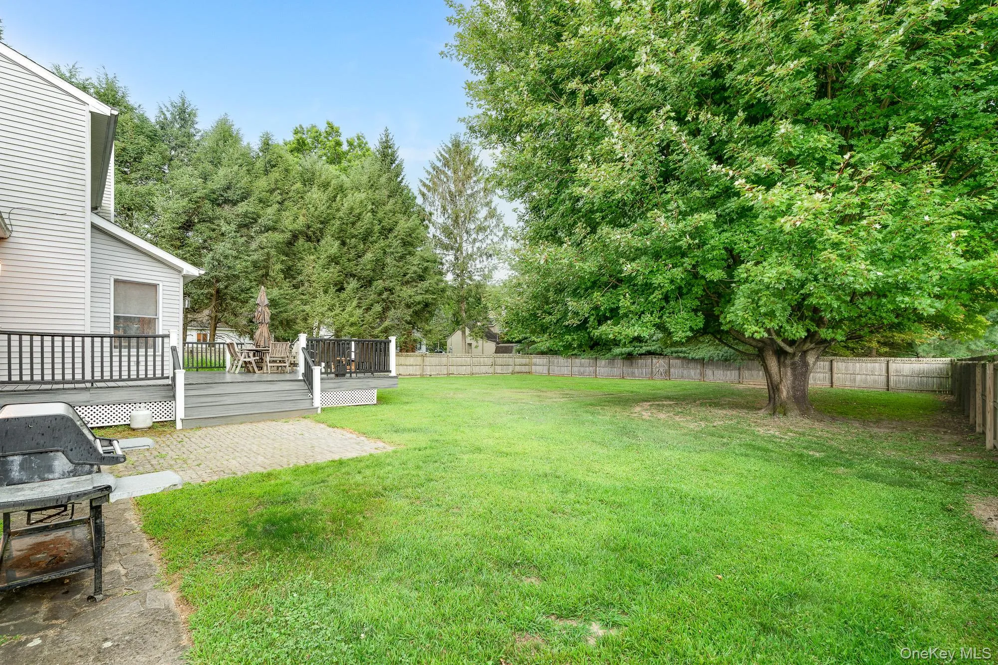 Fenced backyard featuring a deck and view of scattered trees Fenced backyard featuring a deck and view of scattered trees
