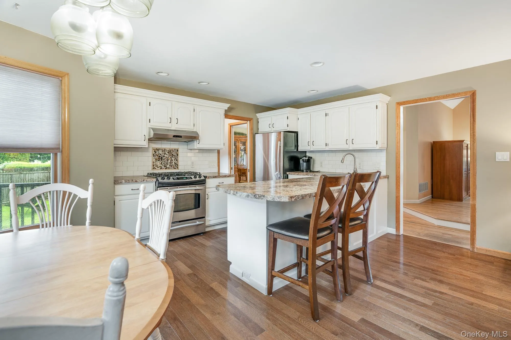 Kitchen featuring a kitchen bar, appliances with stainless steel finishes, light wood-style floors, white cabinetry, and recessed lighting Kitchen featuring a kitchen bar, appliances with stainless steel finishes, light wood-style floors, white cabinetry, and recessed lighting