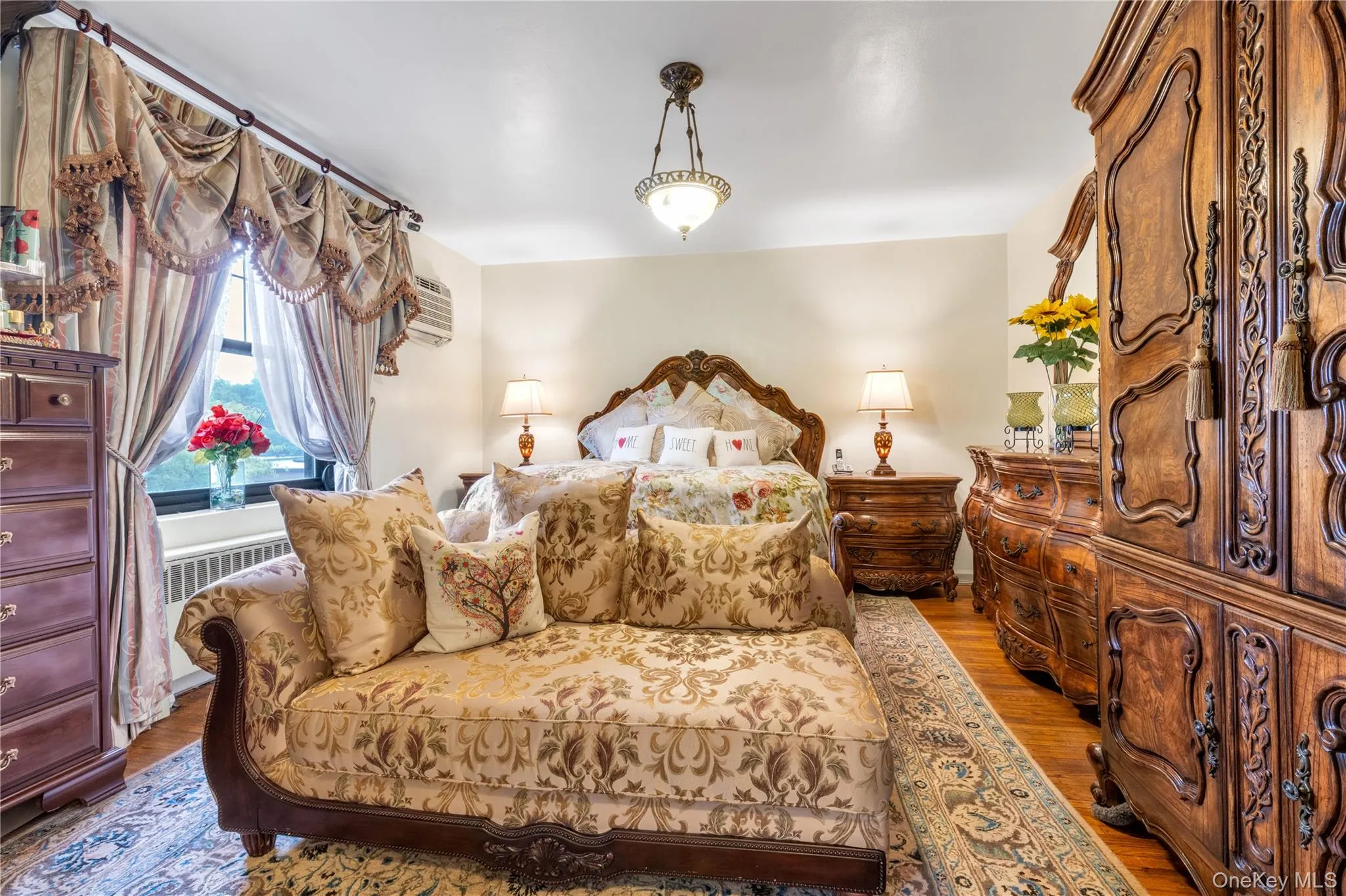 Hardwood flooring, window with natural light, wall-mounted air conditioning unit, and a ceiling-mounted light fixture Hardwood flooring, window with natural light, wall-mounted air conditioning unit, and a ceiling-mounted light fixture