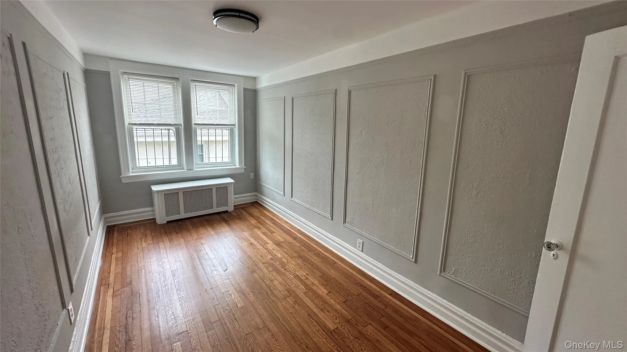 Hardwood flooring, decorative wall molding, dual windows, and ceiling-mounted light fixture Hardwood flooring, decorative wall molding, dual windows, and ceiling-mounted light fixture
