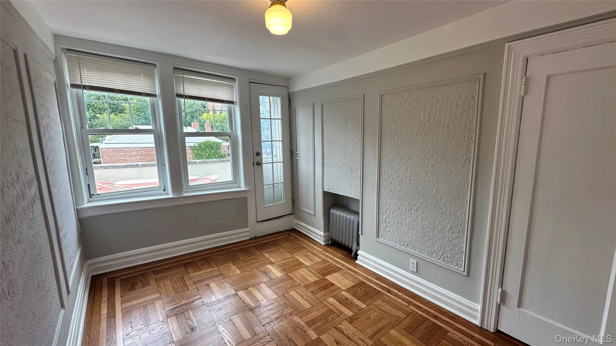 Parquet wood flooring, decorative wall molding, multiple windows, glass-paned door, and a built-in radiator Parquet wood flooring, decorative wall molding, multiple windows, glass-paned door, and a built-in radiator
