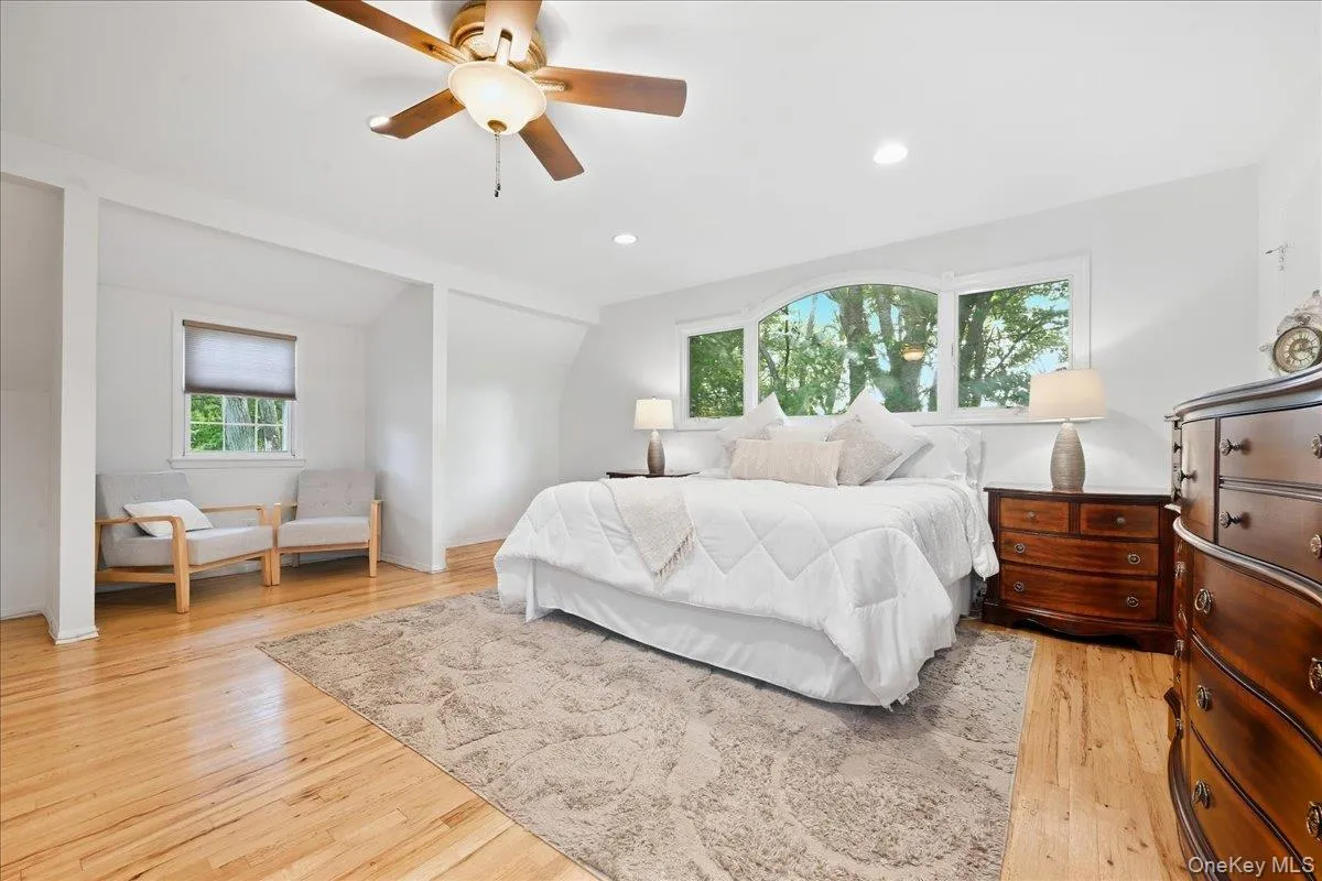 Primary Bedroom Bright interior with wood-finish flooring, a ceiling fan, recessed lighting, and a large arched window Primary Bedroom Bright interior with wood-finish flooring, a ceiling fan, recessed lighting, and a large arched window