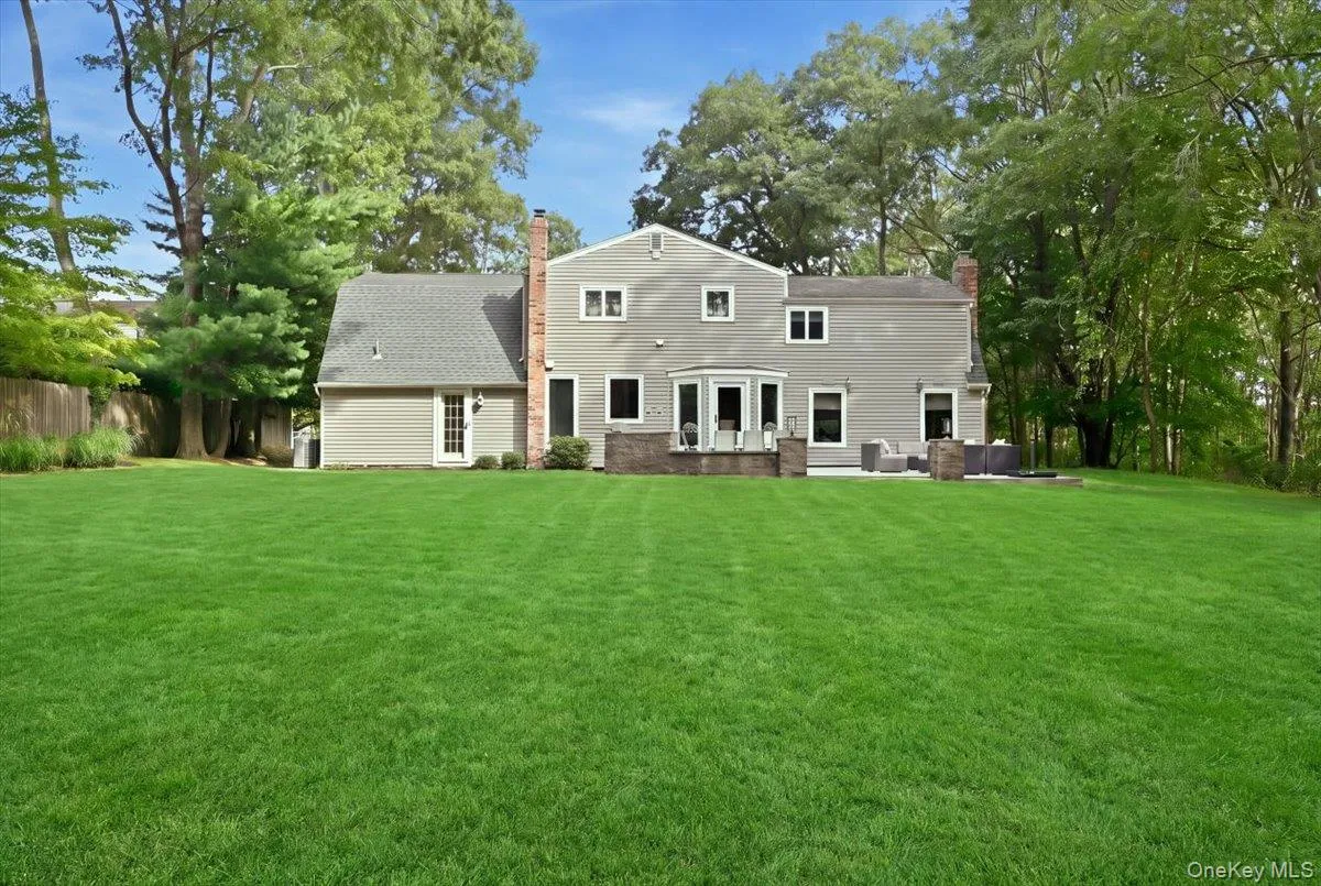 Expansive manicured lawn with mature trees, stone patio, built-in outdoor seating, and a stone fireplace Expansive manicured lawn with mature trees, stone patio, built-in outdoor seating, and a stone fireplace