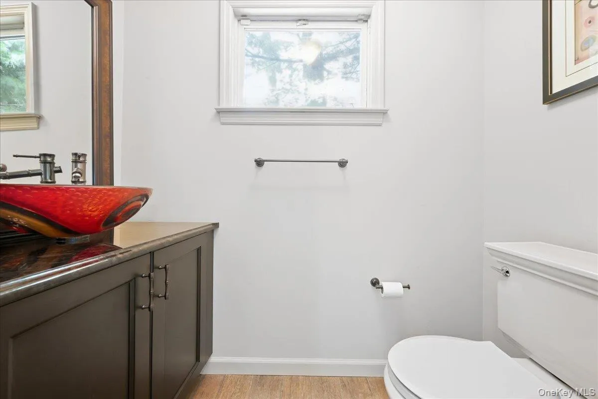 Modern vanity with a red vessel sink, dark countertop, and dark wood-finish cabinet Modern vanity with a red vessel sink, dark countertop, and dark wood-finish cabinet