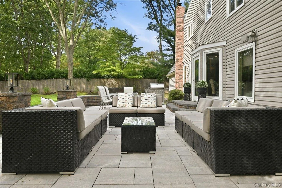 Expansive stone patio with modular seating, stone retaining walls, and surrounding mature trees Expansive stone patio with modular seating, stone retaining walls, and surrounding mature trees