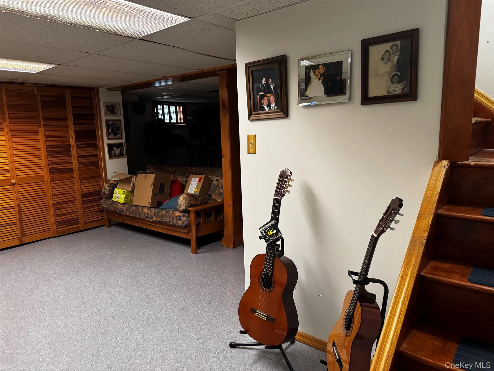 Wood slat bi-fold closet doors, drop ceiling with fluorescent lighting, wood staircase, and wood door frame Wood slat bi-fold closet doors, drop ceiling with fluorescent lighting, wood staircase, and wood door frame