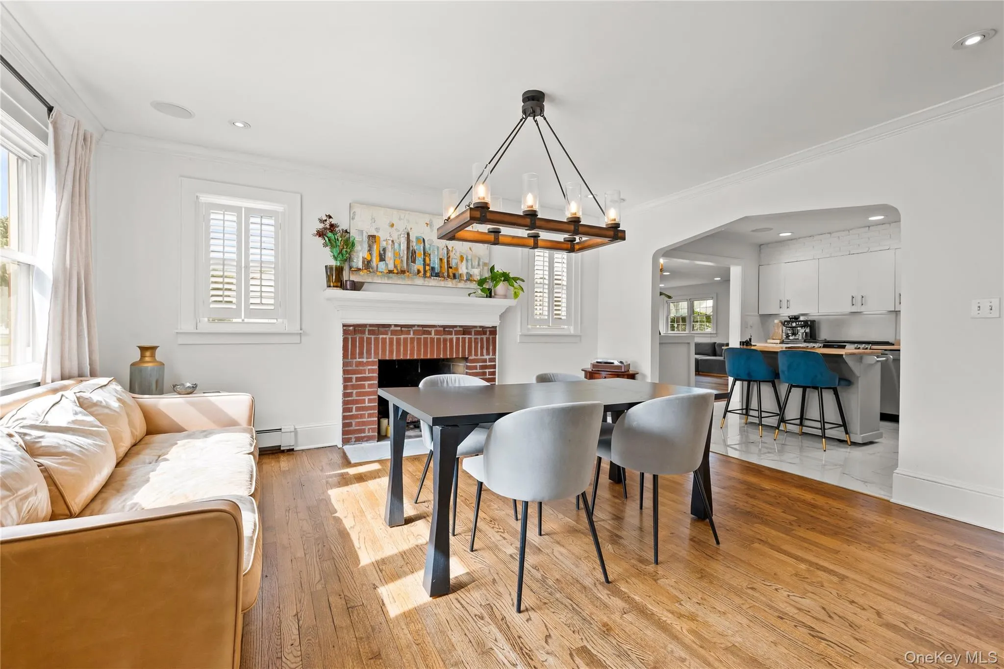 Hardwood flooring, brick fireplace with mantel, recessed lighting, and a kitchen pass-through with built-in cabinetry Hardwood flooring, brick fireplace with mantel, recessed lighting, and a kitchen pass-through with built-in cabinetry