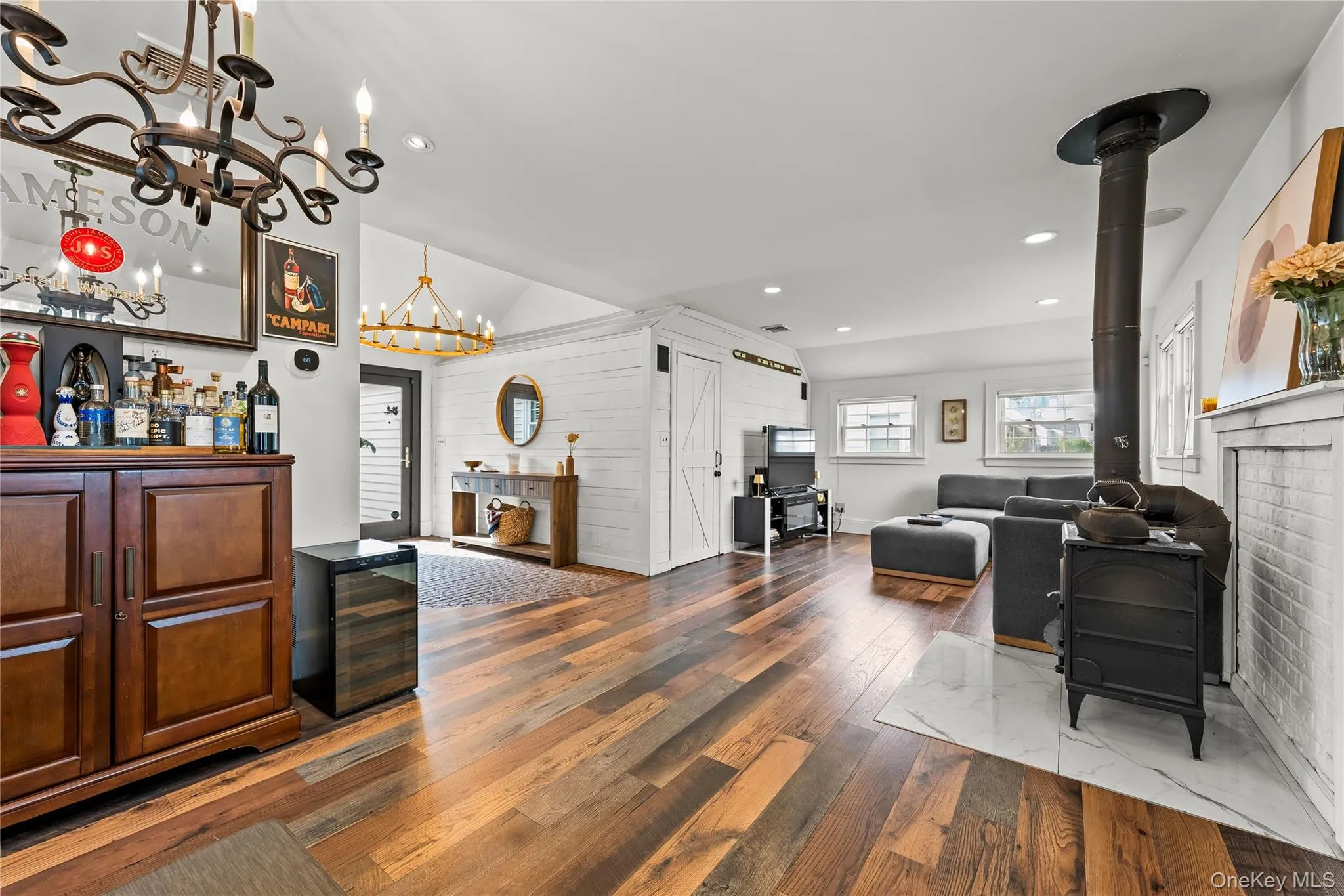 Open living room with hardwood floors, wood-burning stove, built-in bar cabinetry and recessed lighting flowing to the dining area Open living room with hardwood floors, wood-burning stove, built-in bar cabinetry and recessed lighting flowing to the dining area