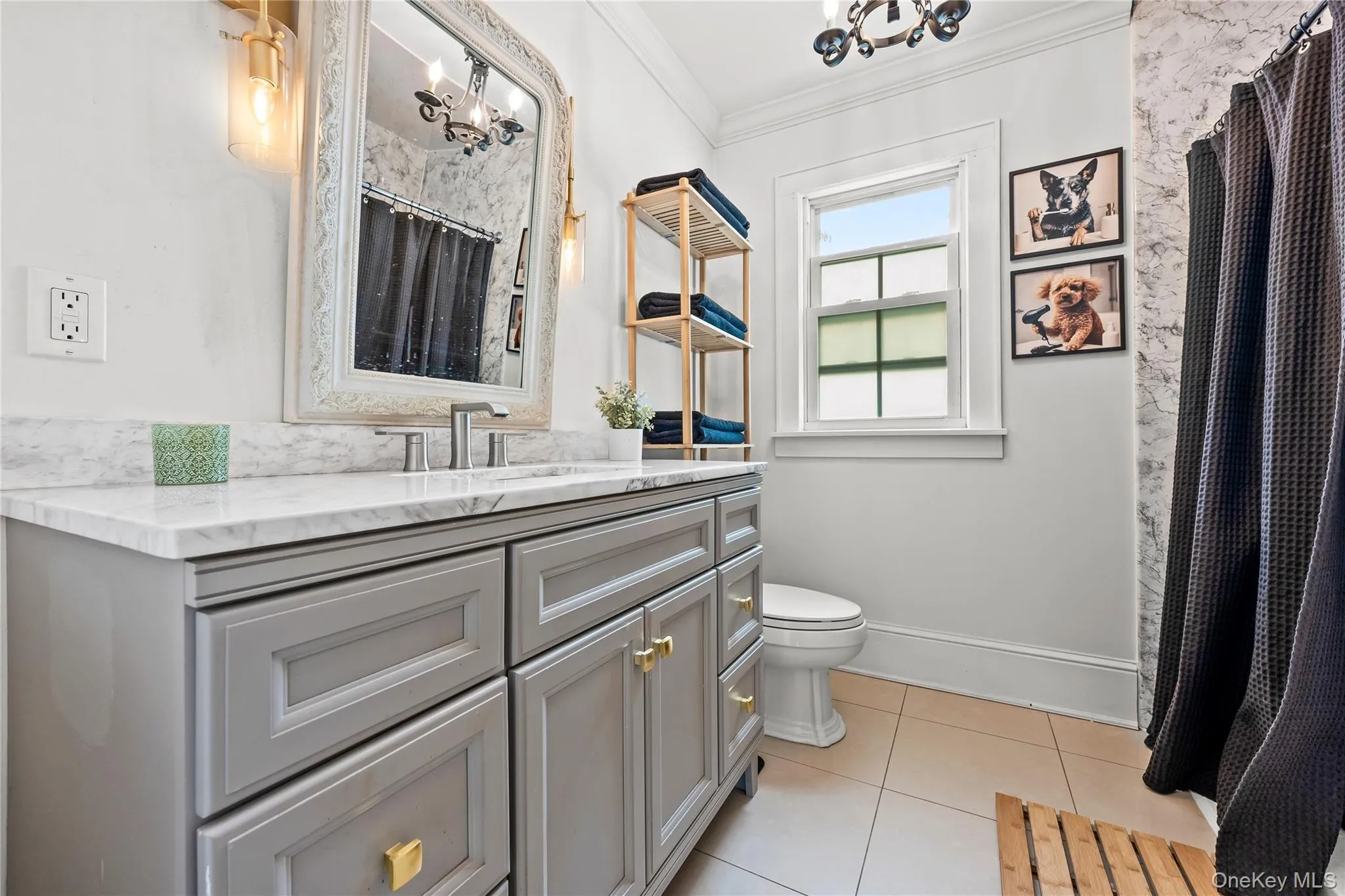 Bathroom featuring a light gray vanity with gold-tone hardware, a white countertop, and a vanity mirror with integrated lighting Bathroom featuring a light gray vanity with gold-tone hardware, a white countertop, and a vanity mirror with integrated lighting