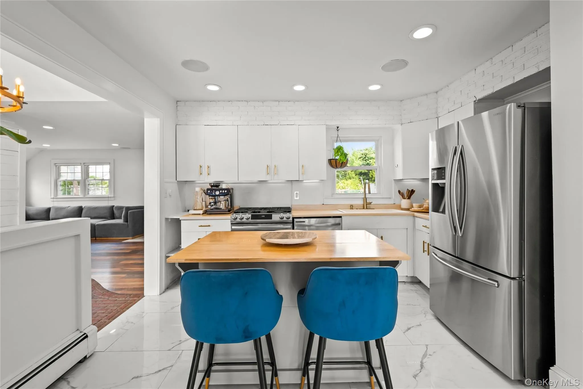 Modern kitchen featuring white cabinetry, stainless steel appliances, wood-finish countertops, recessed lighting, and large format tile flooring Modern kitchen featuring white cabinetry, stainless steel appliances, wood-finish countertops, recessed lighting, and large format tile flooring