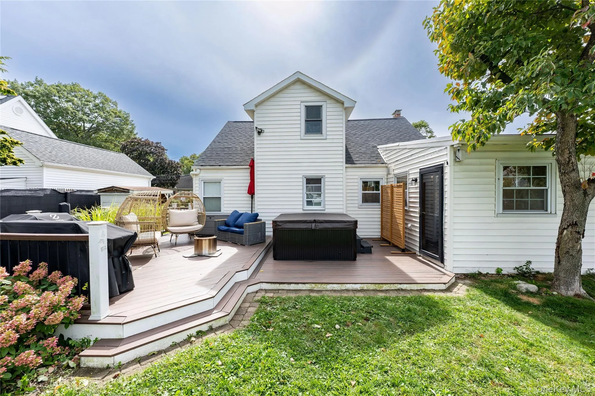 Rear view of the house with multi-level composite deck, white vinyl siding and fenced backyard Rear view of the house with multi-level composite deck, white vinyl siding and fenced backyard