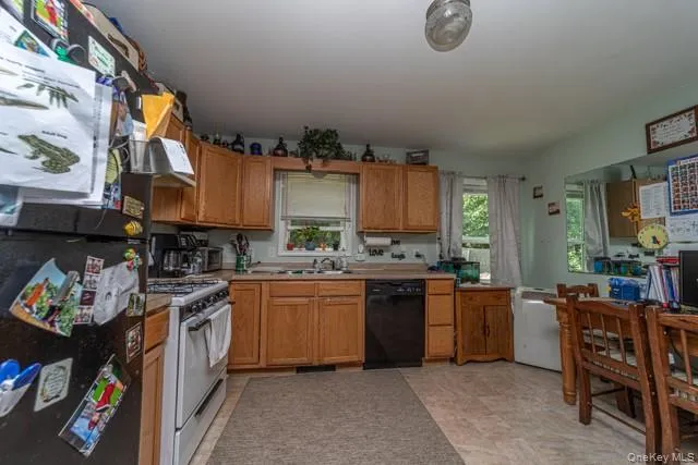 Kitchen featuring wood cabinetry, a white gas range, and a black dishwasher Kitchen featuring wood cabinetry, a white gas range, and a black dishwasher
