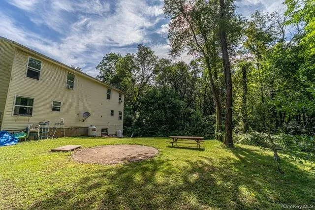 Expansive grassy yard with mature trees and a circular gravel patio area Expansive grassy yard with mature trees and a circular gravel patio area