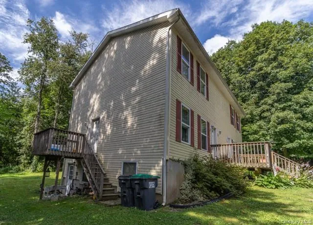 Two-story exterior with siding, featuring multiple windows with shutters and two wooden decks Two-story exterior with siding, featuring multiple windows with shutters and two wooden decks