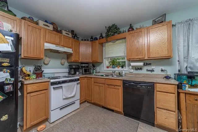 Kitchen featuring wood-finish cabinetry, a white gas range, and a black dishwasher Kitchen featuring wood-finish cabinetry, a white gas range, and a black dishwasher