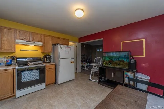 Kitchen with wood cabinetry, laminate countertops, and a white refrigerator Kitchen with wood cabinetry, laminate countertops, and a white refrigerator