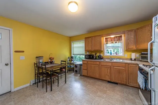 Kitchen featuring wood-finish cabinetry, a stainless steel sink, and a four-burner gas range Kitchen featuring wood-finish cabinetry, a stainless steel sink, and a four-burner gas range