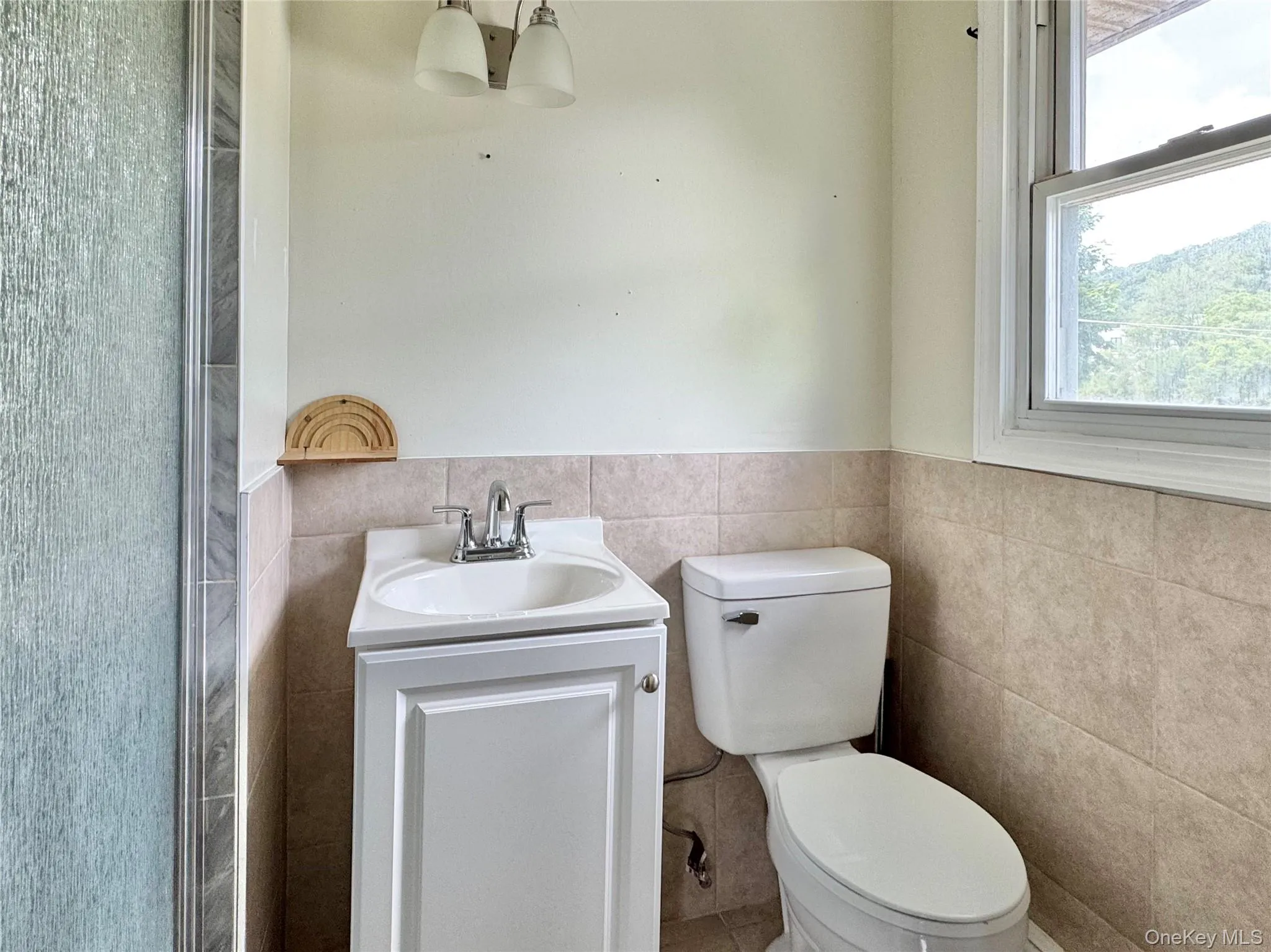 Bathroom featuring tile walls, vanity, and wainscoting Bathroom featuring tile walls, vanity, and wainscoting