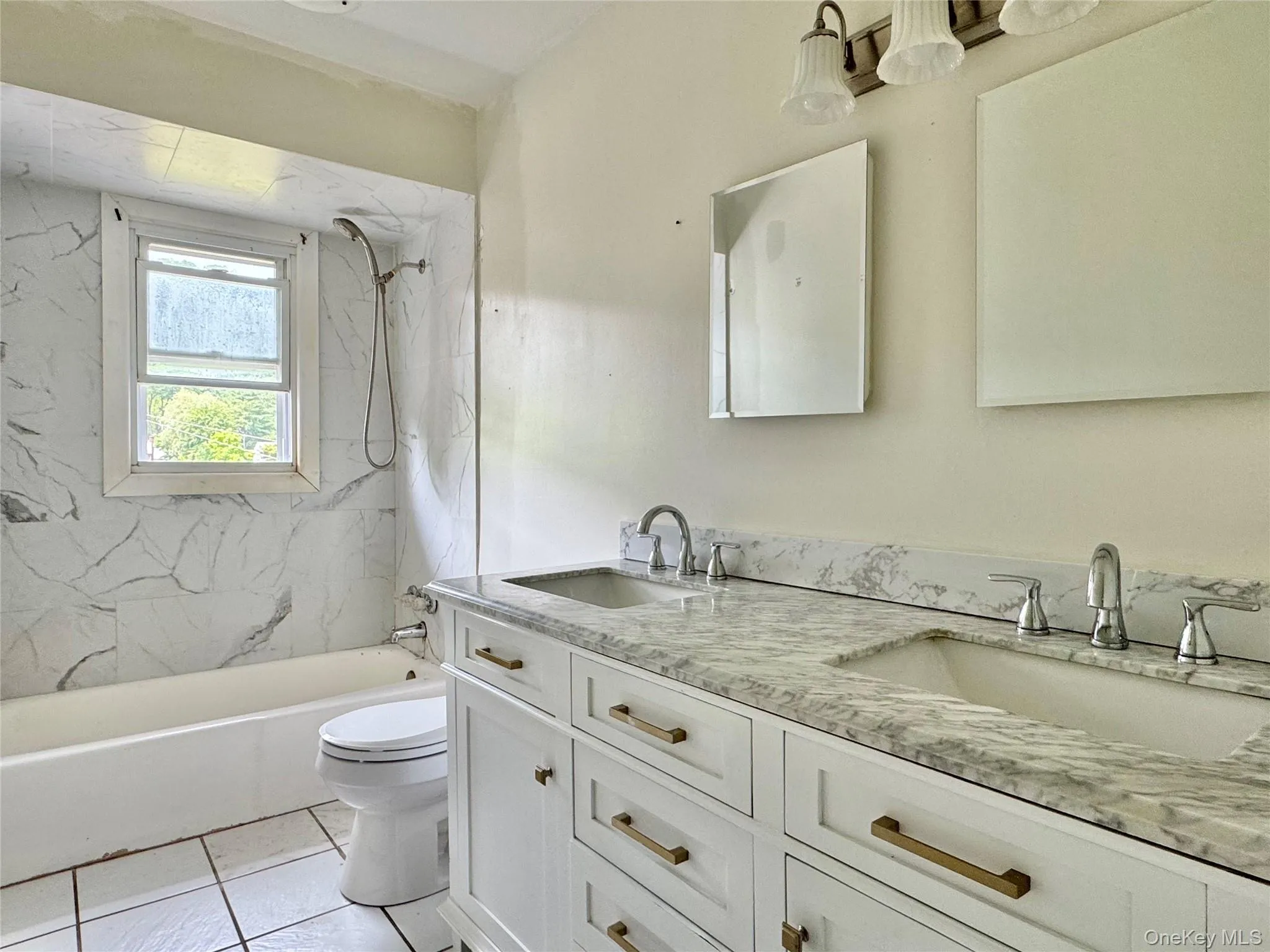 Full bathroom featuring double vanity, tub / shower combination, and tile patterned flooring Full bathroom featuring double vanity, tub / shower combination, and tile patterned flooring