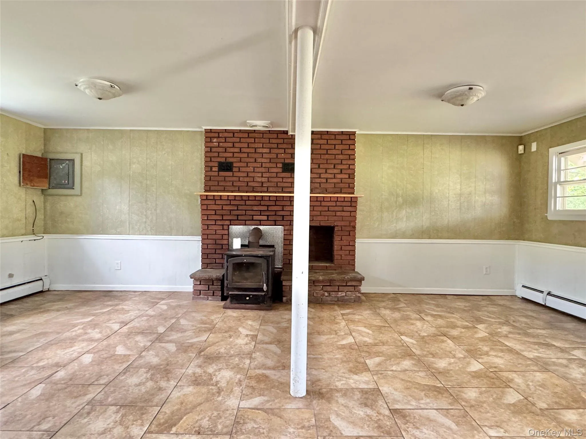 Unfurnished living room featuring ornamental molding and a wood stove Unfurnished living room featuring ornamental molding and a wood stove