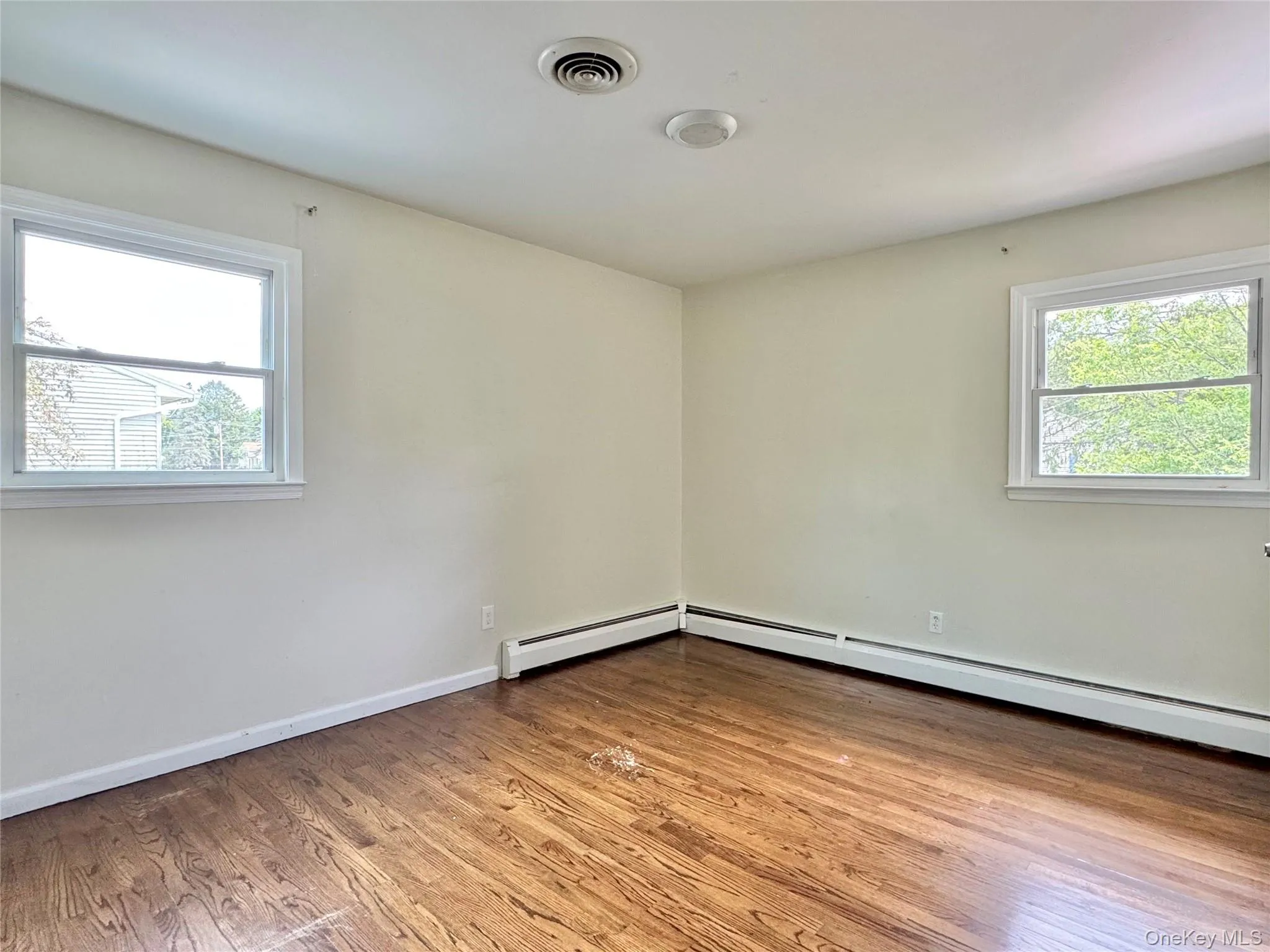 Spare room featuring wood finished floors and baseboard heating Spare room featuring wood finished floors and baseboard heating