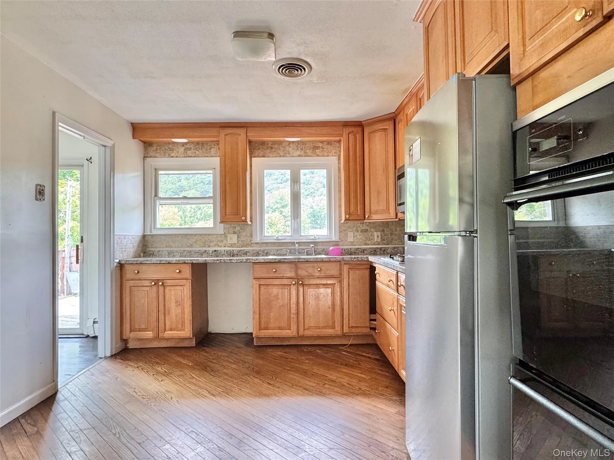Kitchen featuring freestanding refrigerator, light wood-style floors, and tasteful backsplash Kitchen featuring freestanding refrigerator, light wood-style floors, and tasteful backsplash