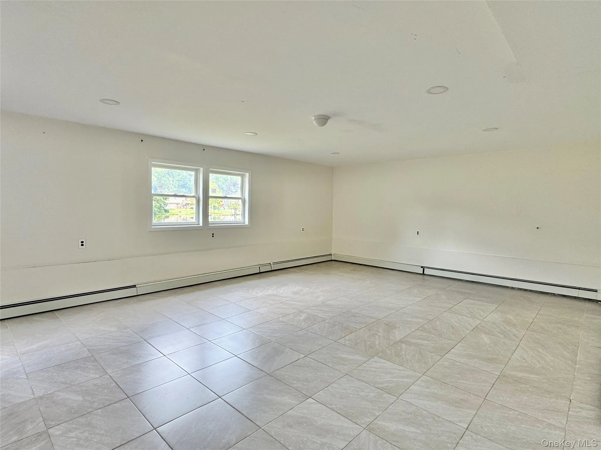 Spare room with baseboard heating and light tile patterned floors Spare room with baseboard heating and light tile patterned floors