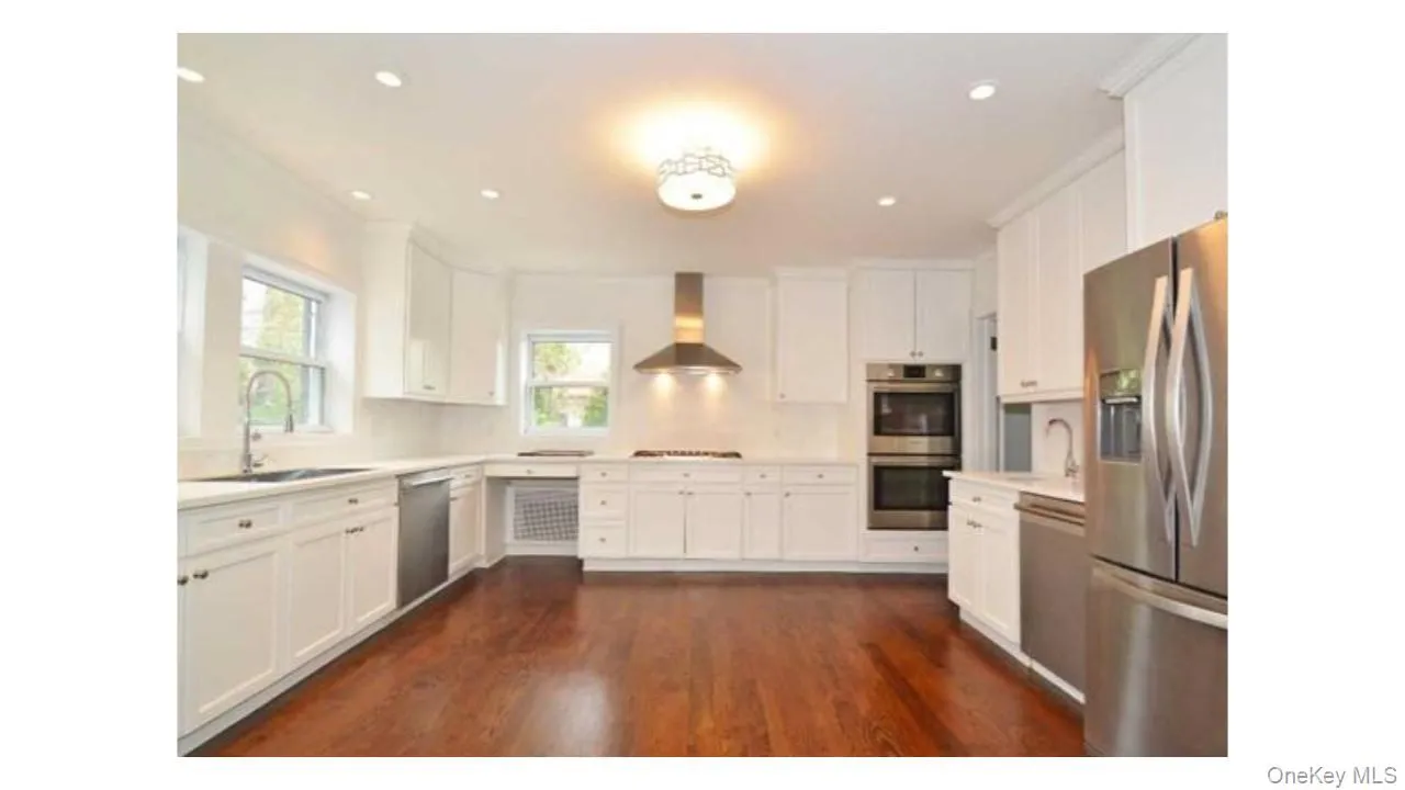White cabinetry with stainless steel appliances, recessed lighting, wood-finish flooring, and a built-in double oven White cabinetry with stainless steel appliances, recessed lighting, wood-finish flooring, and a built-in double oven