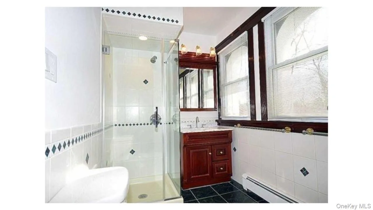 Glass-enclosed shower with white tiled walls Glass-enclosed shower with white tiled walls