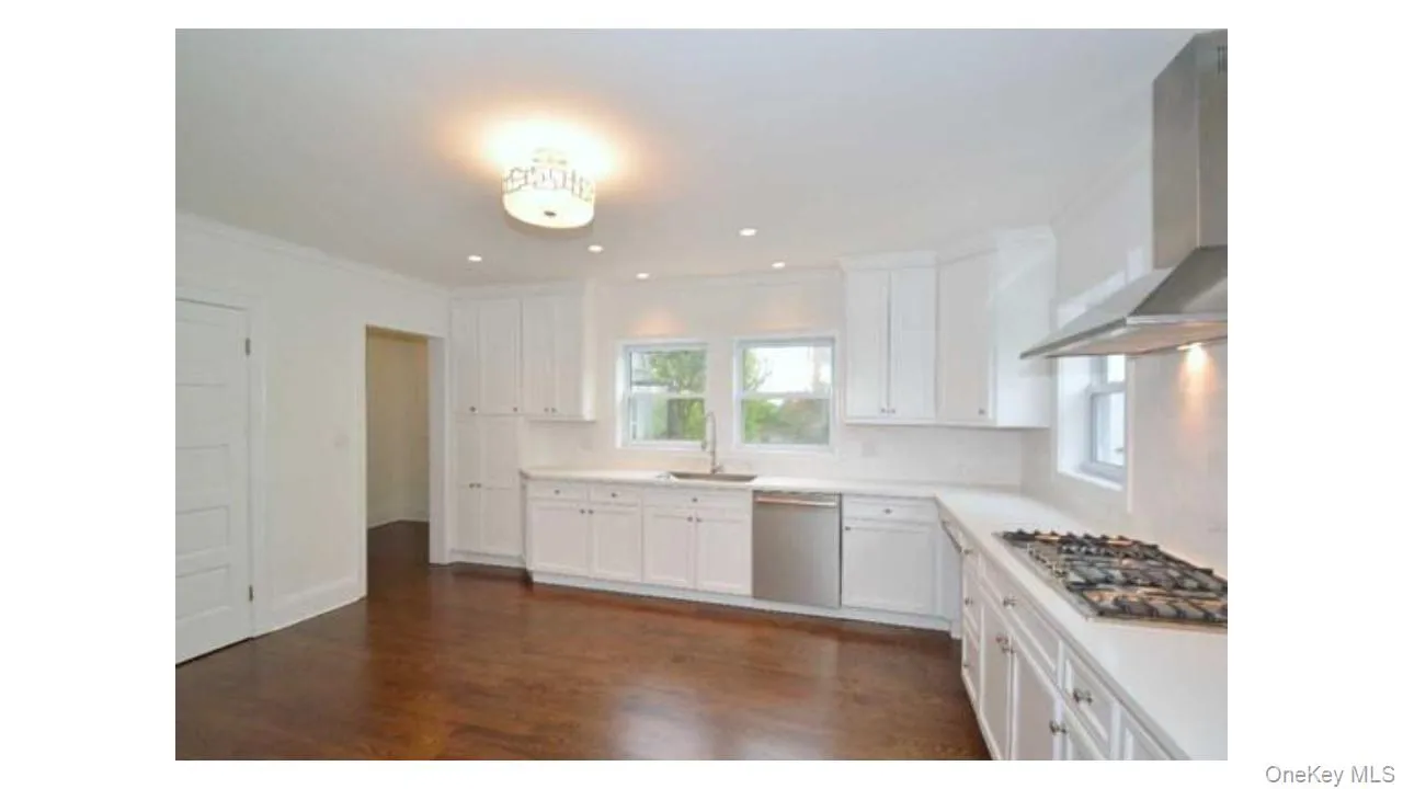 Kitchen featuring white shaker cabinetry, stainless steel appliances, recessed lighting, and wood-finish flooring Kitchen featuring white shaker cabinetry, stainless steel appliances, recessed lighting, and wood-finish flooring